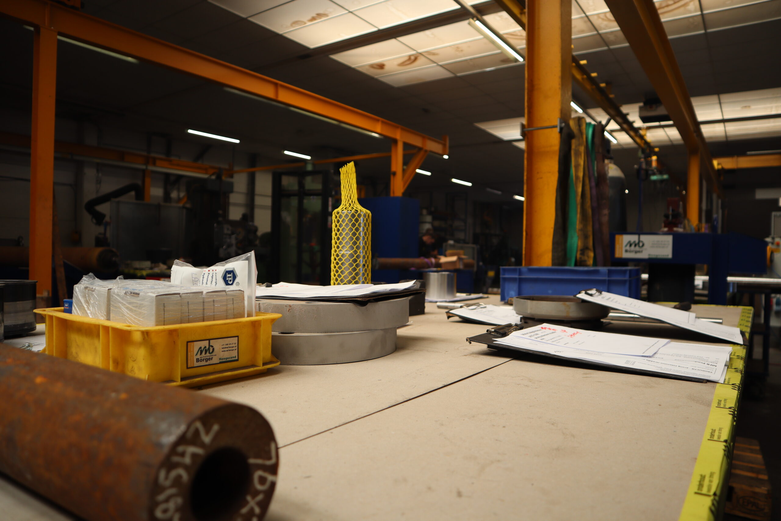 Werkbank in het magazijn van Machinefabriek Börger met metalen onderdelen, werkbonnen en hulpmaterialen.